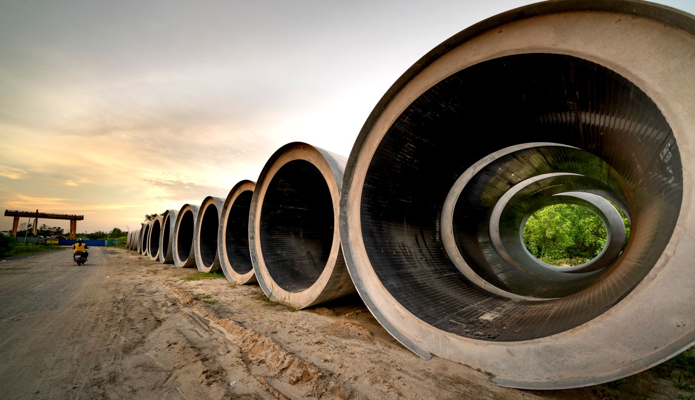 Large sewer pipes staged for installation at sunset